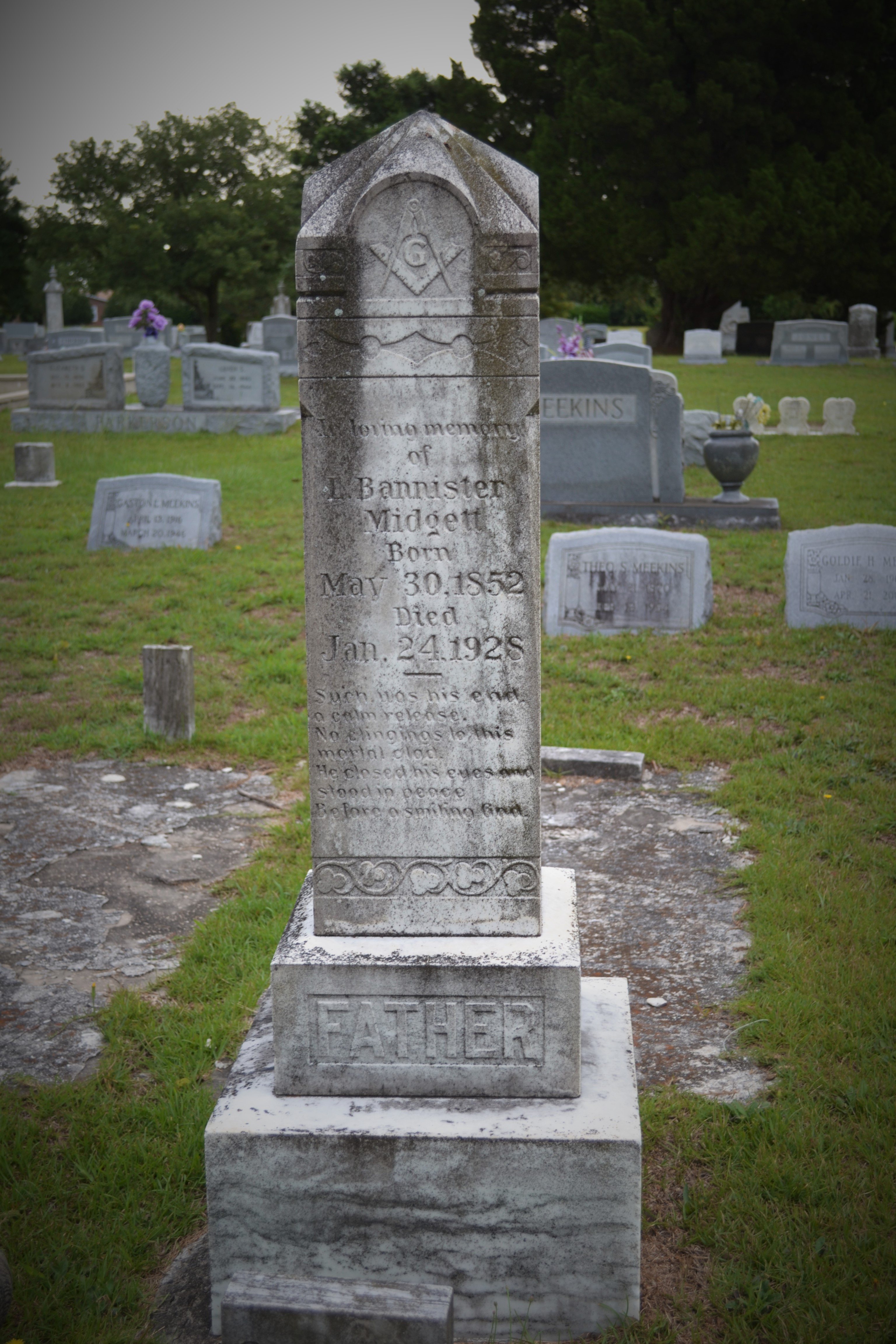 A gravestone for Midgett sits in a cemetery. It is a marble obelisk.
